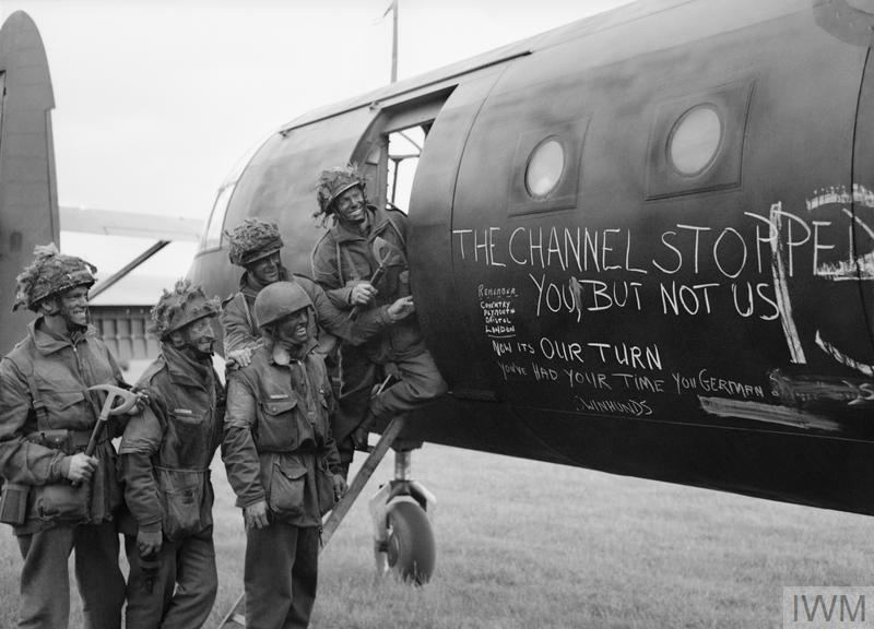 Glider troops pose next to their aircraft. THe slogan "The channel stopped you but not us" has been written in chalk on the fuselage.