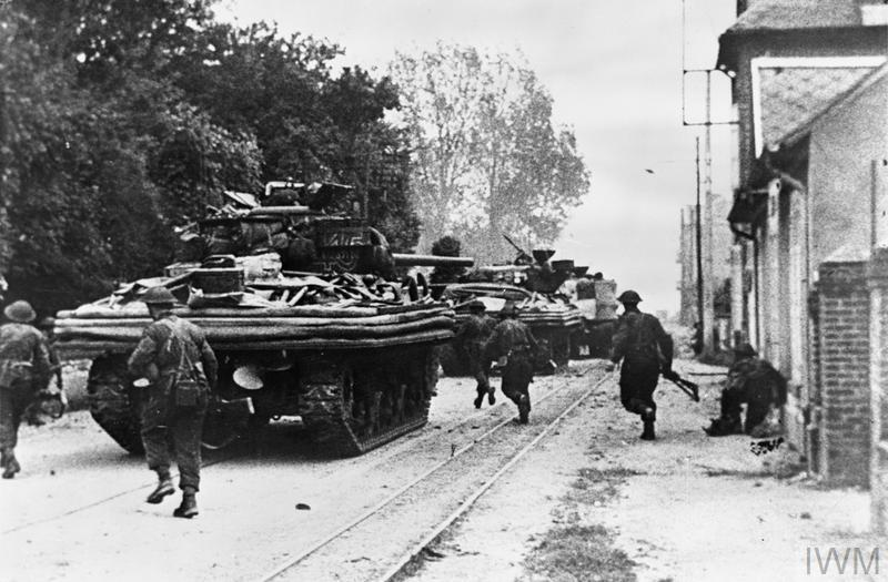 British tanks and infantry advancing down a Normandy road