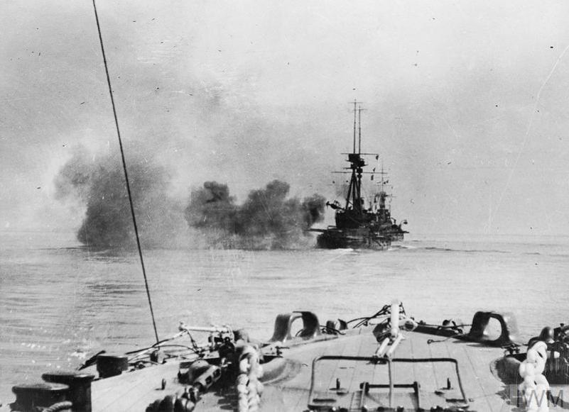 A WW1-era French Battleship opening fire with smoke pouring from the gun barrels.