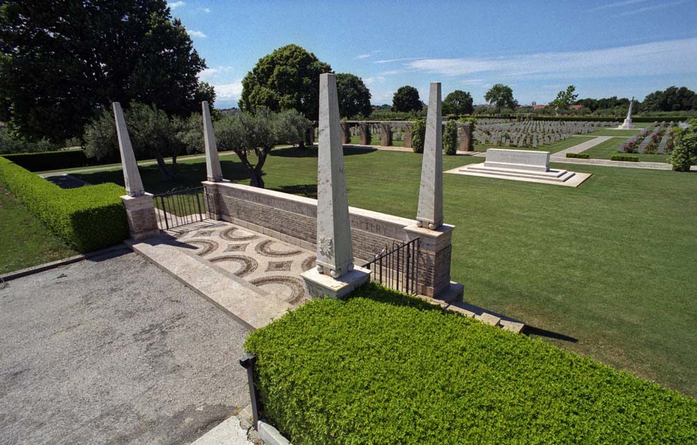 Entrance of the Moro River Canadian War Cemetery showing the four obelisk adornments and mosaic tiling of the entry war. In the background, the Cross of Sacrifice and Stone of Remembrance can be seen.