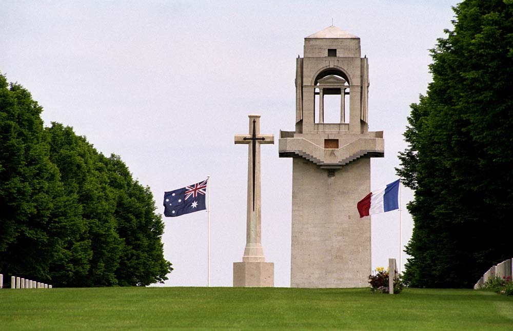 Close up of the Villers-Bretonneux Memorial's central tower set next to the Cross of Sacrifice and Australian and French Flags.