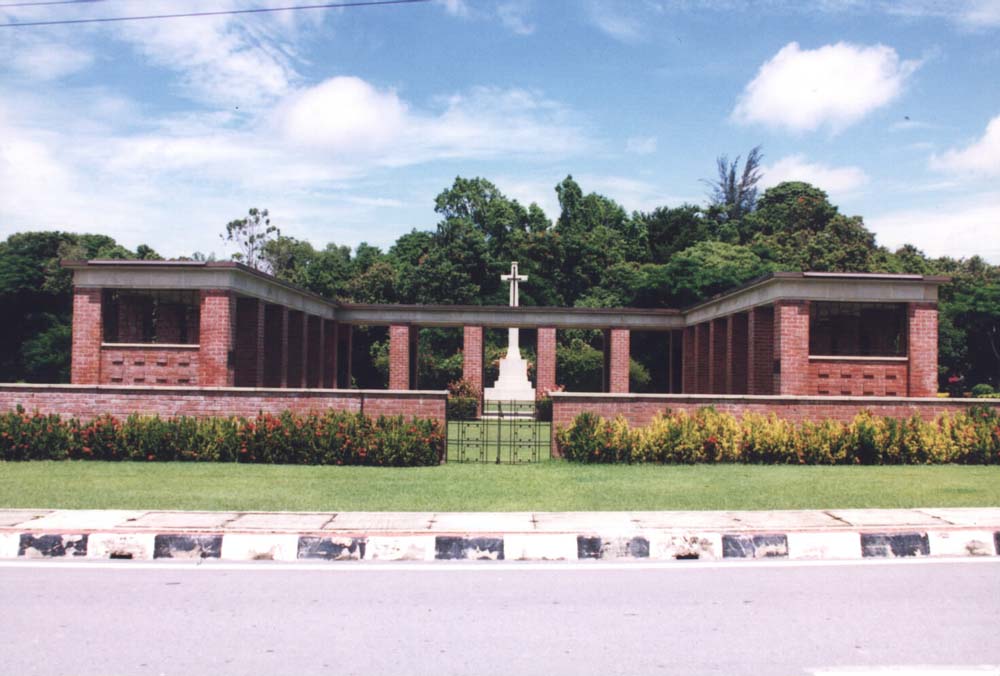 Shot of the Labuan Memorial showing its Red Brick Colonnades with the Cross of Sacrifice set in front of the main memorial structure.
