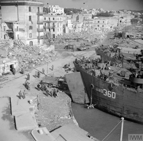 Allied soldiers move equipment off landing ships in the ruins of Anzio's port.