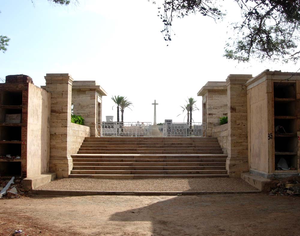 The gates to Tripoli War Cemetery set between two redstone pillars atop a stone staircase.
