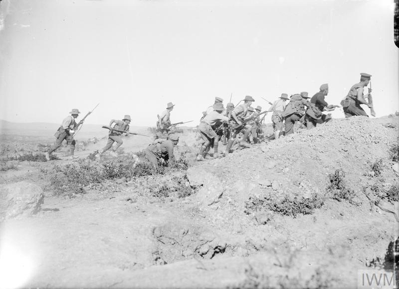 WW1 era Australian infantry charging uphill across a rocky landscape.