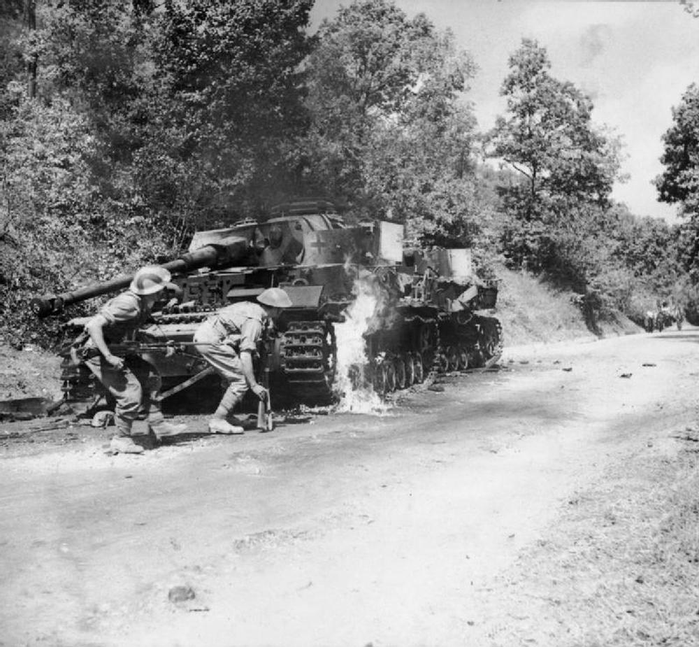 British soldiers advance passed knocked out Wehrmacht tanks.