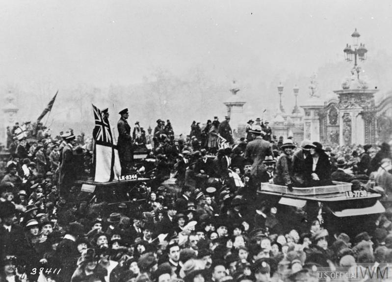 Black and white photo showing a large group of people gathered outside the gates of Buckingham Palace to celebrate the signing of the Armistice, November 1918.