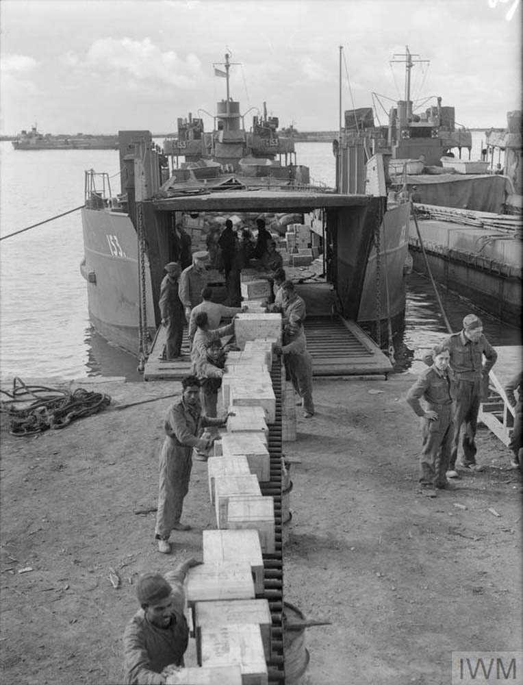Military troops unloading cargo through a tank transporter boat.