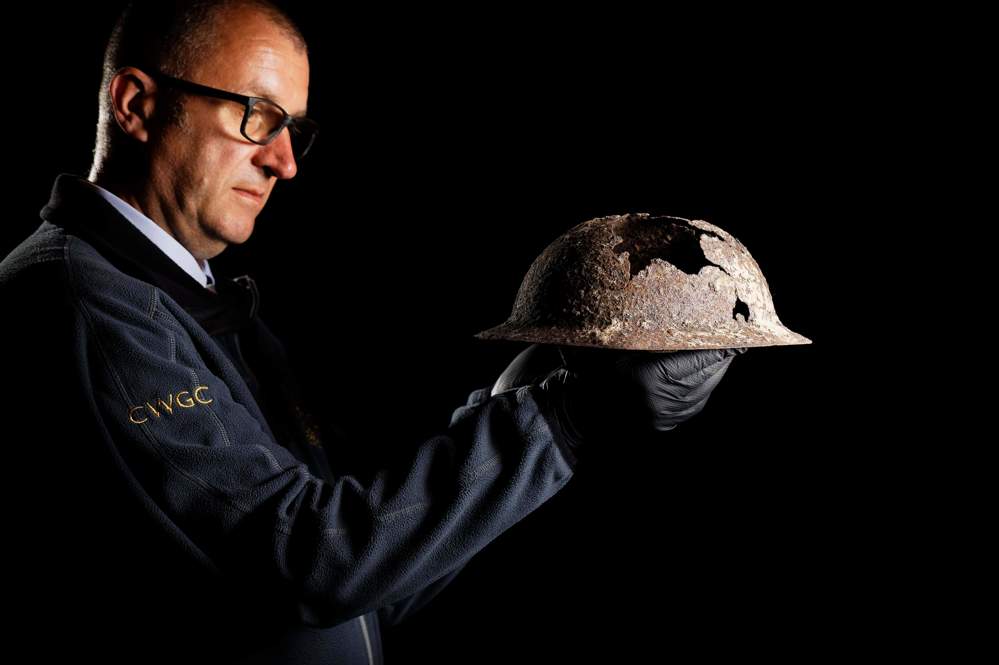 CWGC staff member holding up helmet