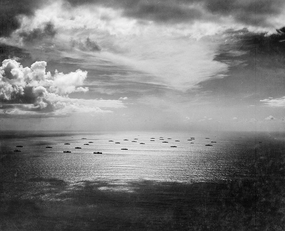 Black and white photo of a convoy made of merchant naval vessels and Royal Navy escort ships.